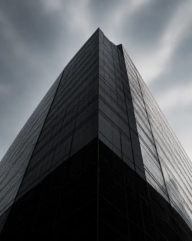 Edificio corporativo de fachada oscura fotografiado en contrapicado